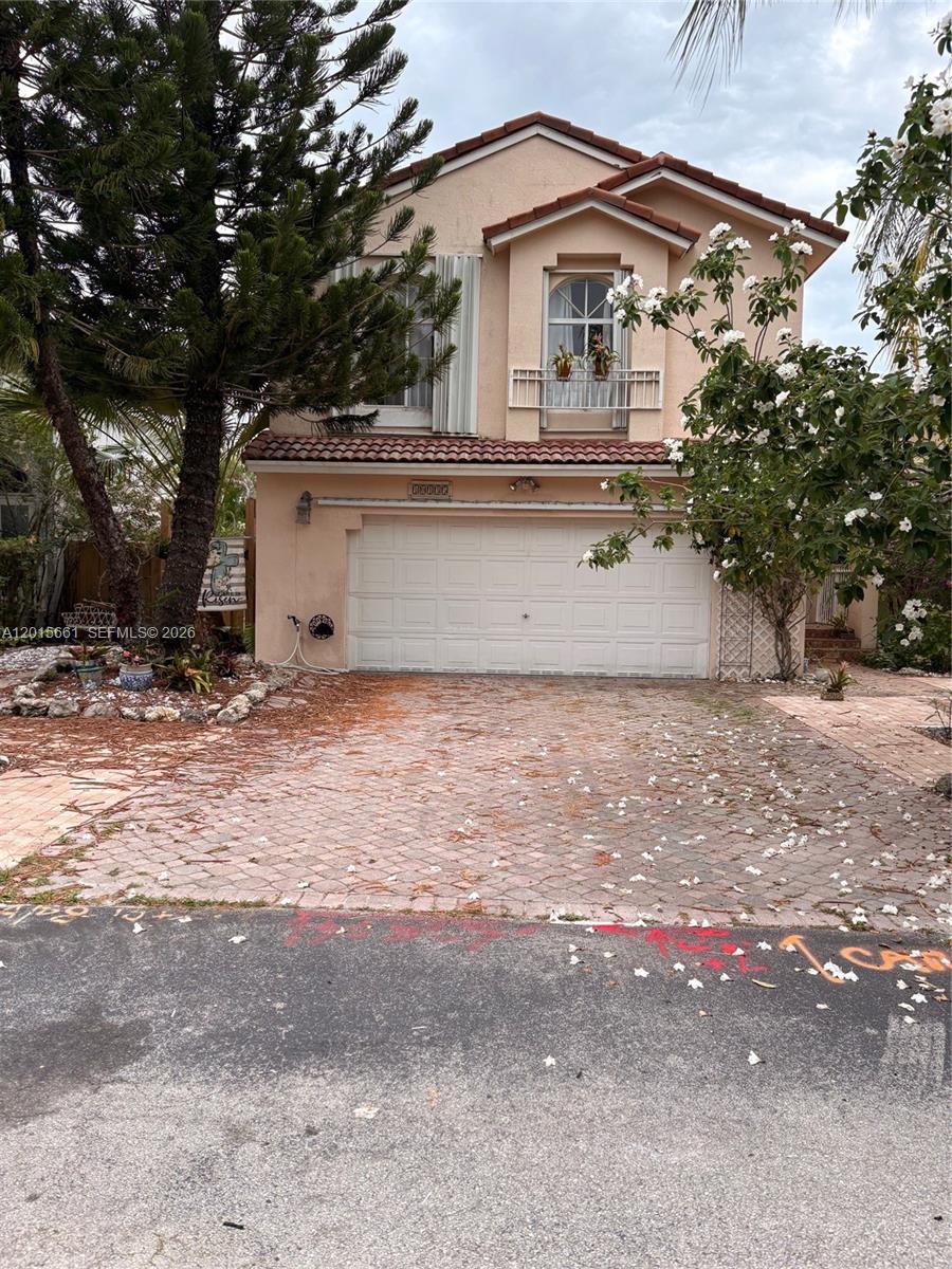 A two-story stucco house features a white garage door and a paved driveway — 10135 SW 156th Ave, Miami FL 33196, MIAMI, FL
