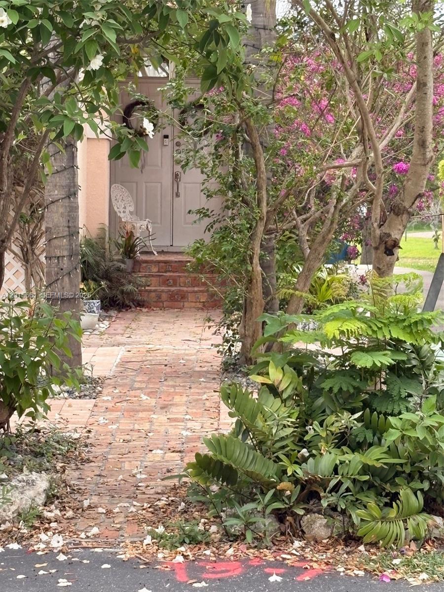 A brick walkway leads to a set of double doors with a small white chair — 10135 SW 156th Ave, Miami FL 33196, MIAMI, FL