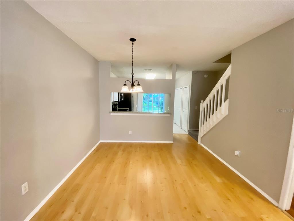 An interior view of a room with light wood flooring, beige walls, and an open door — 12415 BERKELEY SQUARE DRIVE, TAMPA, FL