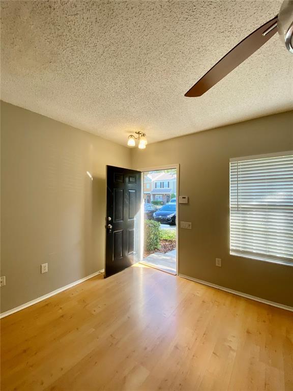 A living room with light wood flooring, a ceiling fan, and an open doorway to a bathroom — 12415 BERKELEY SQUARE DRIVE, TAMPA, FL