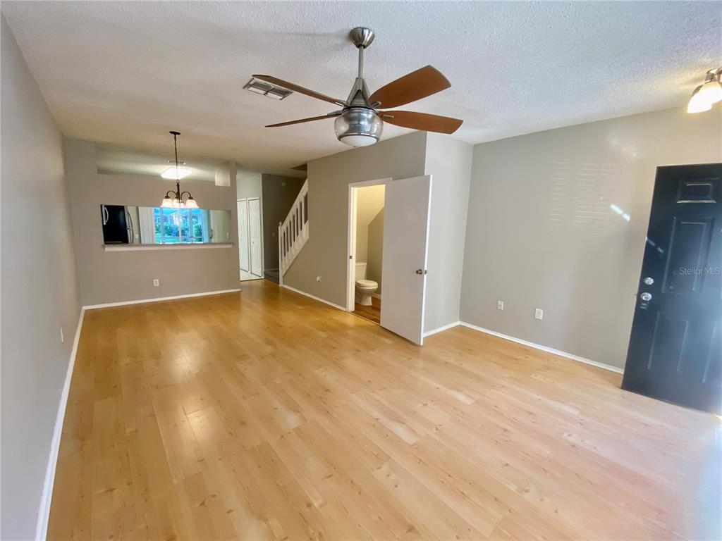 An empty living room features light wood flooring, a ceiling fan, and a pass-through window — 12415 BERKELEY SQUARE DRIVE, TAMPA, FL