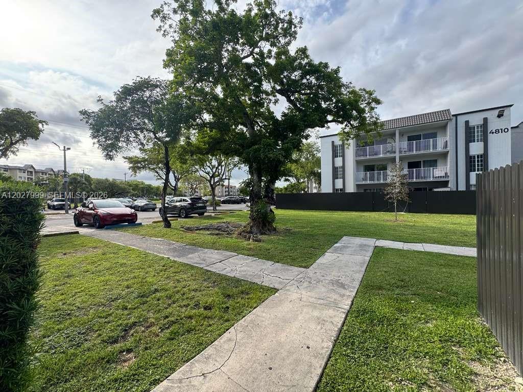 A view of a grassy courtyard with a large tree, a sidewalk, and an apartment building — 4800 NW 79th Ave # 208, Doral FL 33166, DORAL, FL