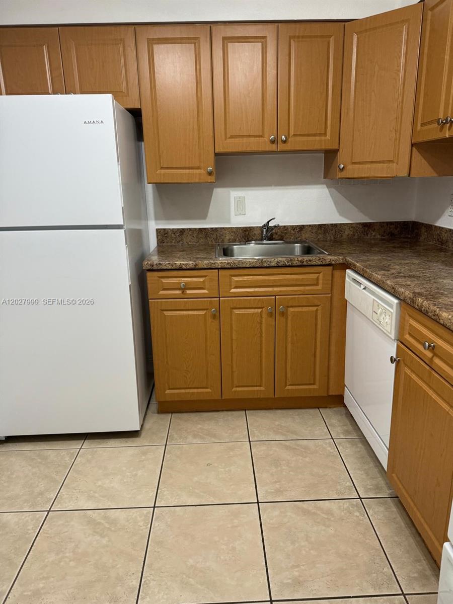 A kitchen features wood cabinets, a white refrigerator, a dishwasher, and a laminate countertop — 4800 NW 79th Ave # 208, Doral FL 33166, DORAL, FL
