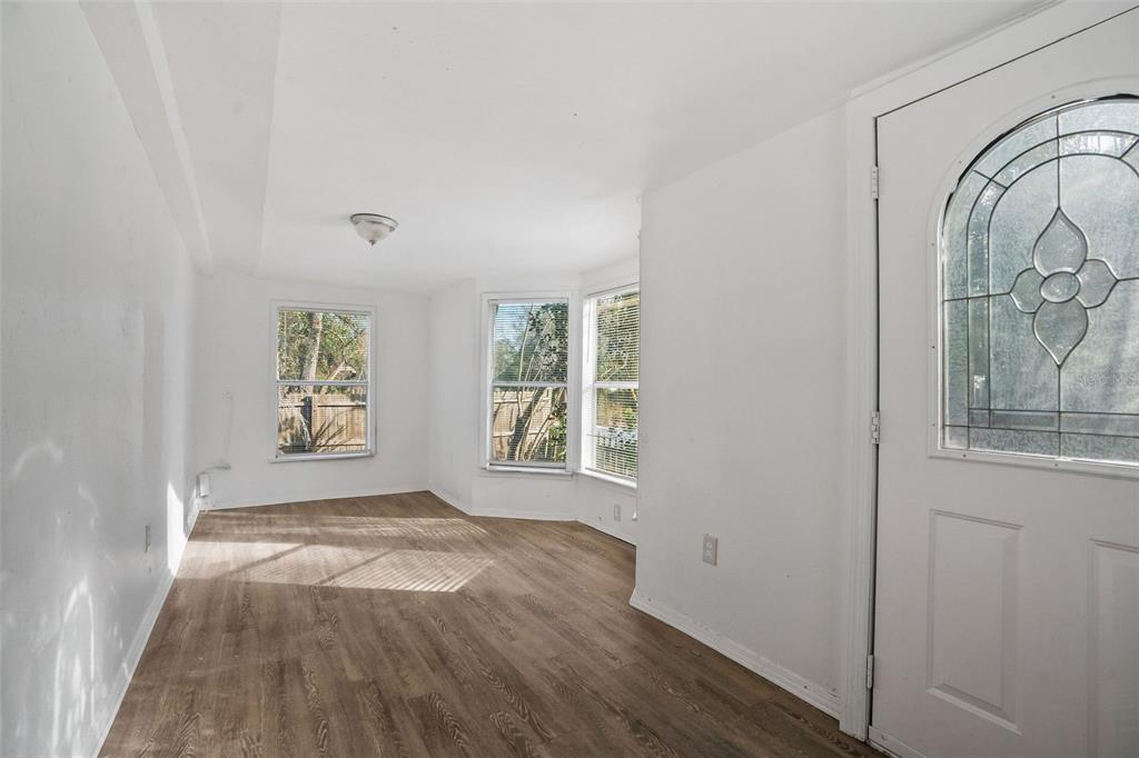 An empty room with white walls, wood-look flooring, a bay window, and a glass-paneled door — 10205 BURTON STREET, NEW PORT RICHEY, FL