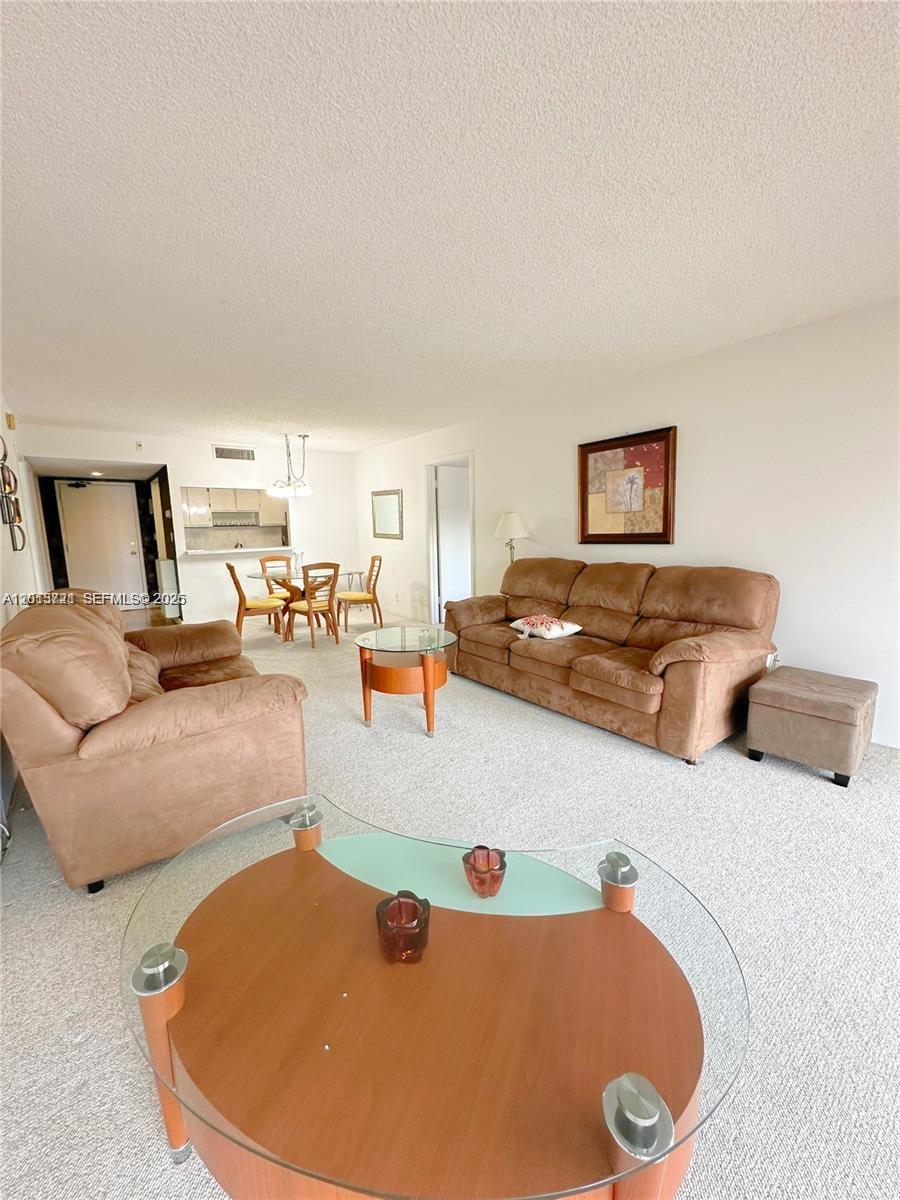 A living room with beige carpet, brown furniture, and an adjacent dining area — 240 Lakeview Dr # 212, Weston FL 33326, WESTON, FL