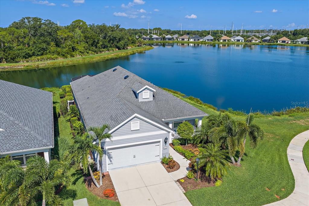 An aerial view shows a gray house with a two-car garage beside a large lake — 4716 CREEKRIDGE COURT, BRADENTON, FL
