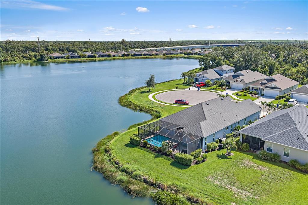 An aerial view of a suburban house with a screened pool overlooking a large lake — 4716 CREEKRIDGE COURT, BRADENTON, FL