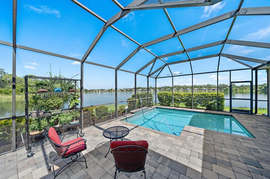 A screened-in patio features a small pool, patio furniture, and a view of a lake — 4716 CREEKRIDGE COURT, BRADENTON, FL