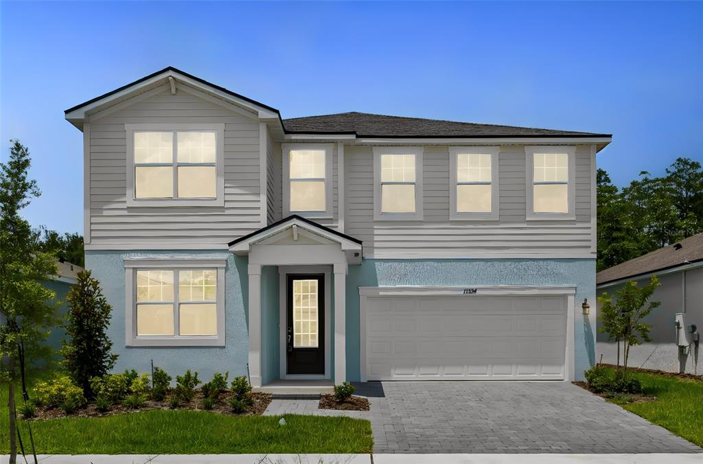 A two-story house with light blue stucco, beige siding, and a two-car garage — 13234 GENERATIONS AVENUE, ORLANDO, FL