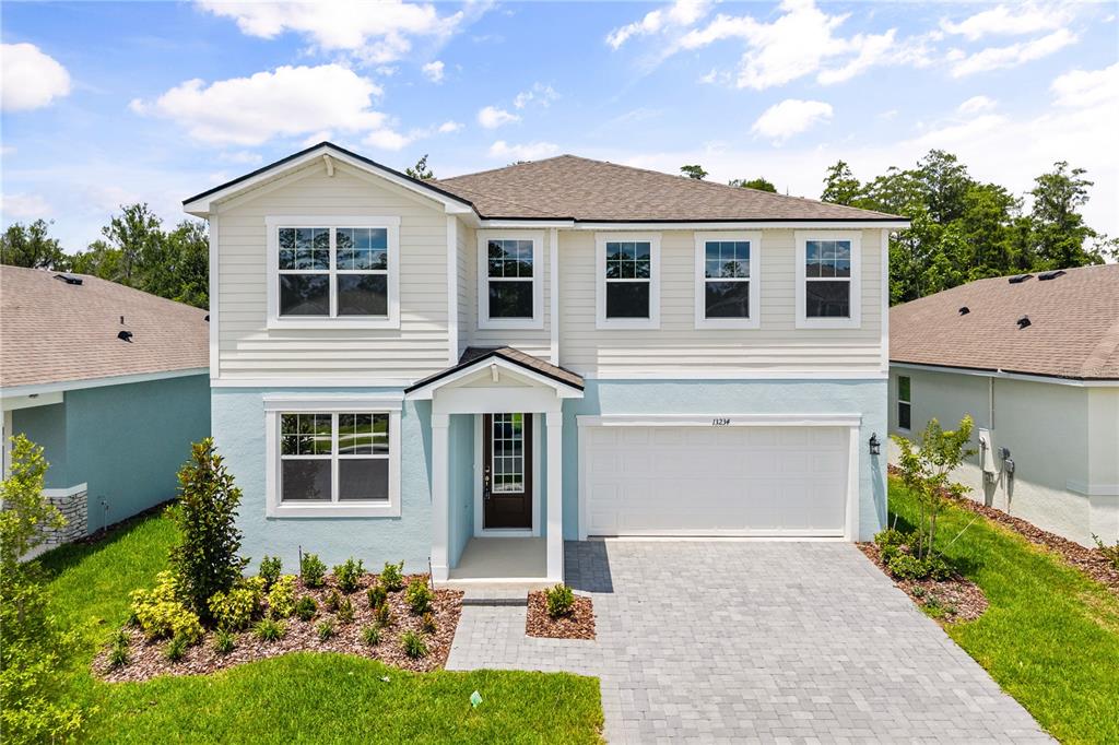 A two-story house with light blue stucco, cream siding, and a paved driveway — 13234 GENERATIONS AVENUE, ORLANDO, FL