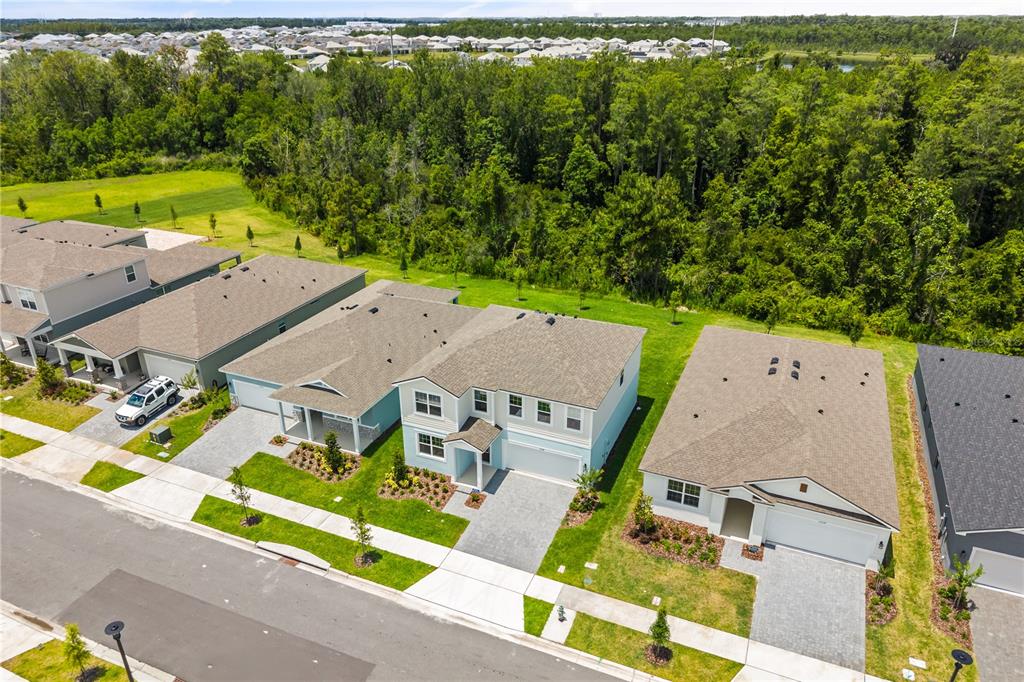 An aerial view shows a row of suburban houses with paved driveways and green lawns — 13234 GENERATIONS AVENUE, ORLANDO, FL