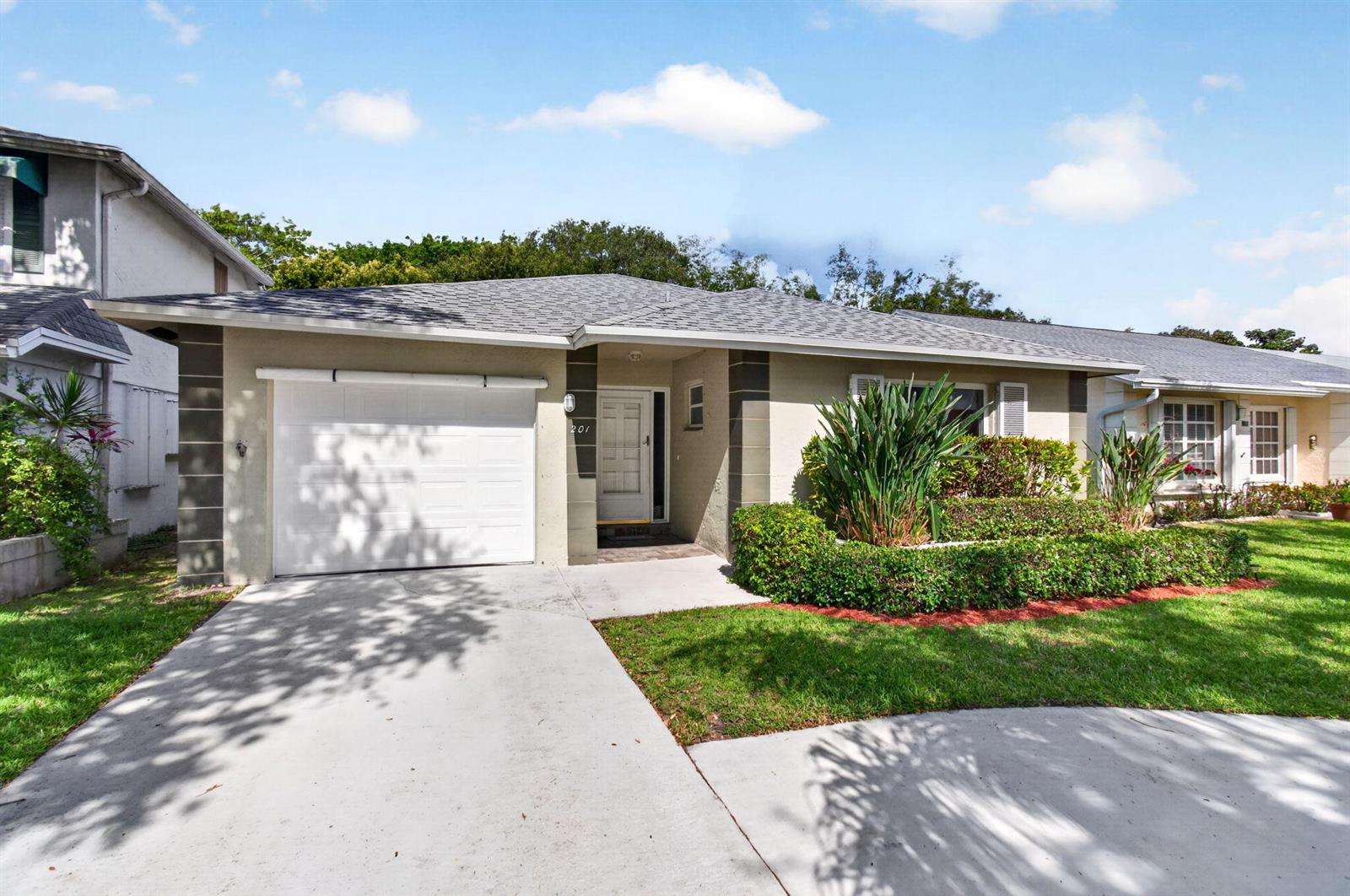 A single-story house with a white garage door, a front entrance, and landscaped front yard — 201 Del Rio Boulevard, Boca Raton FL 33432, BOCA RATON, FL
