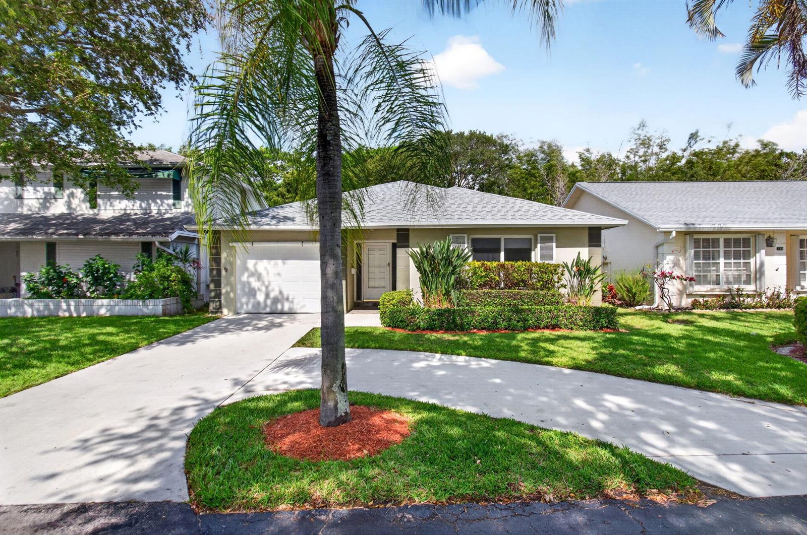 A single-story house with a white garage, a curved driveway, and a palm tree — 201 Del Rio Boulevard, Boca Raton FL 33432, BOCA RATON, FL