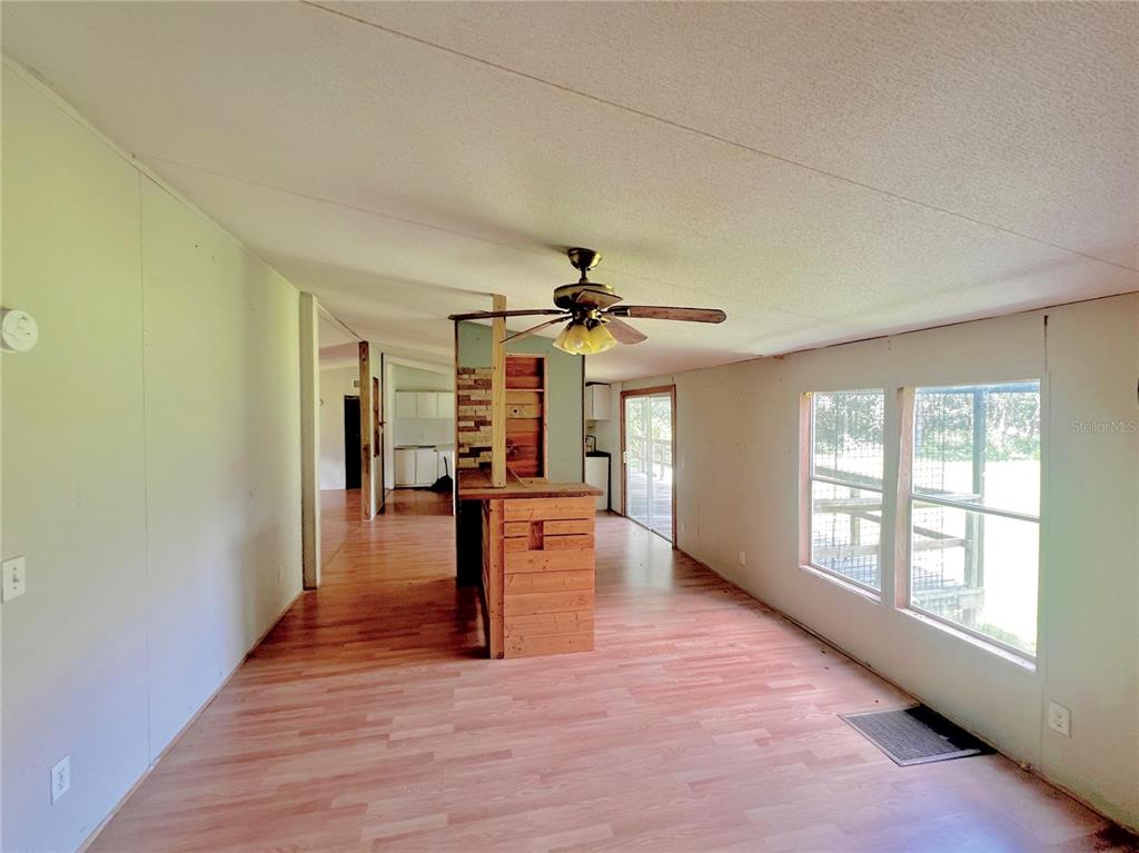 An interior view of a living area with wood-look flooring, a ceiling fan, and partitions — 6487 SPINNER DRIVE, LAKE WALES, FL