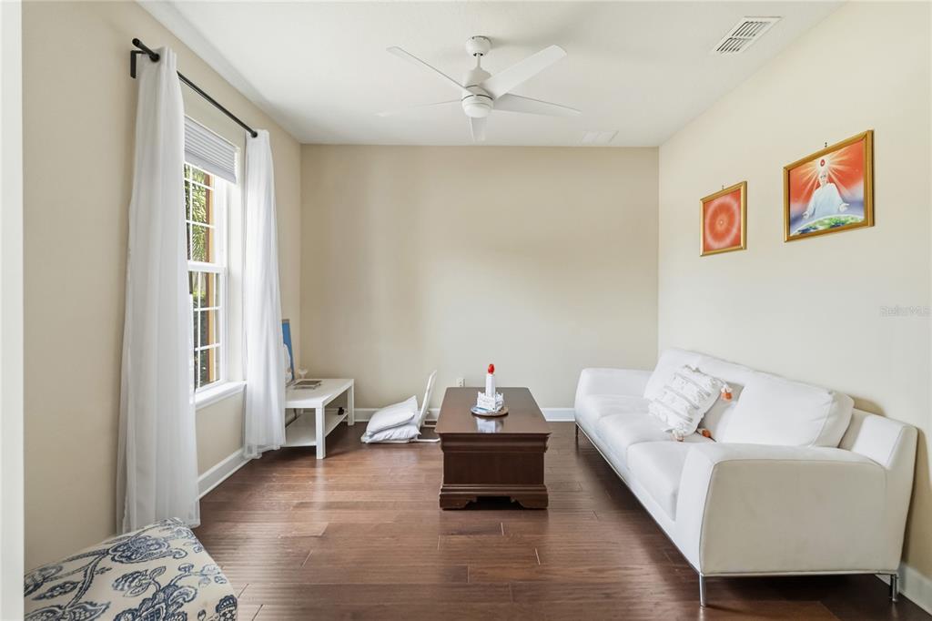 A living room features a white sofa, a dark wood coffee table, and hardwood floors — 12130 ULETA LANE, ORLANDO, FL