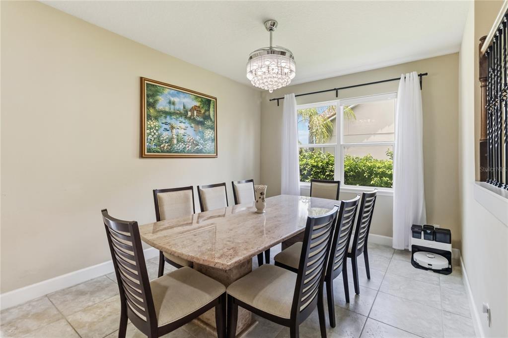 A dining room features a stone-topped table, six chairs, a crystal chandelier, and tile flooring — 12130 ULETA LANE, ORLANDO, FL