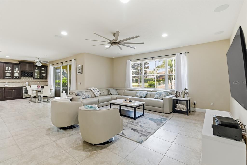 A living room with a large sectional, two swivel chairs, and a dining area nearby — 12130 ULETA LANE, ORLANDO, FL