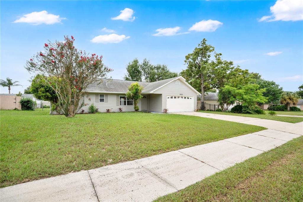 A single-story house with light siding, a two-car garage, and a large front lawn — 3023 INDIA BOULEVARD, DELTONA, FL