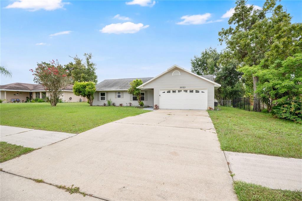 A single-story house with light siding, a two-car garage, and a concrete driveway — 3023 INDIA BOULEVARD, DELTONA, FL