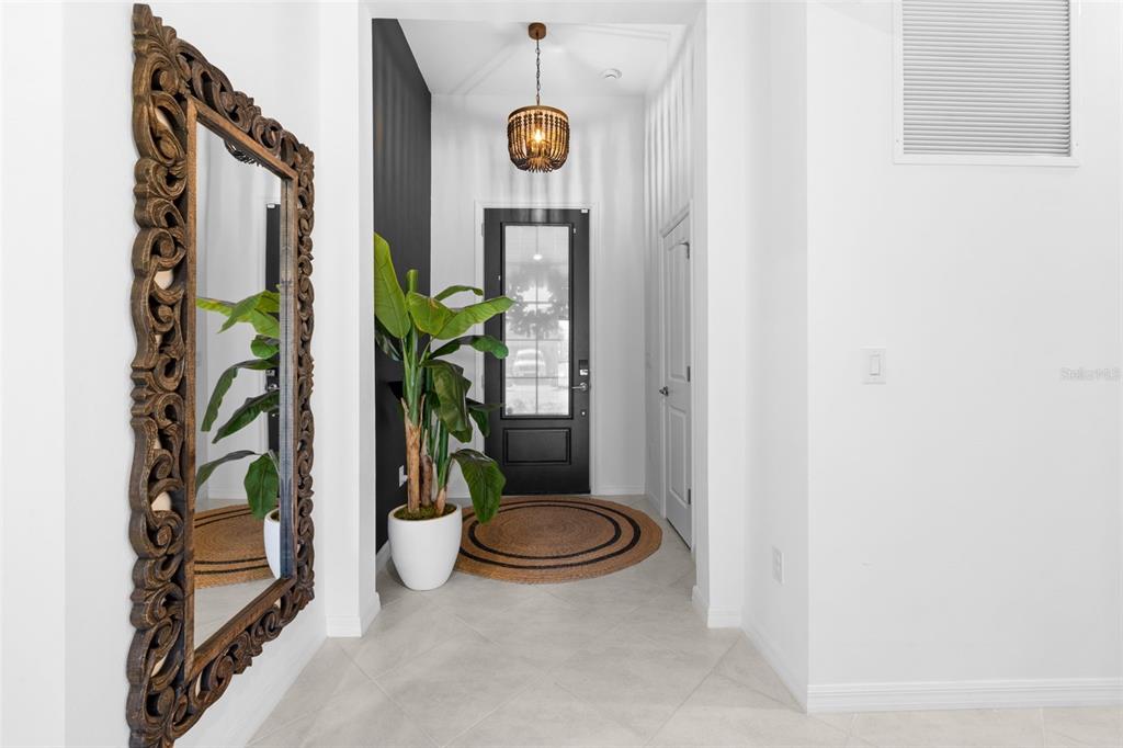 A bright entryway features a large ornate mirror, a potted plant, and a dark door — 1842 W ISLES ROAD, PORT CHARLOTTE, FL