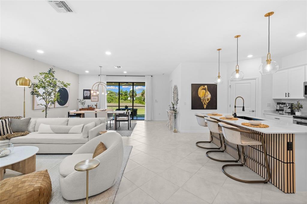 An open-concept living room and kitchen featuring white tile floors and a large sliding door — 1842 W ISLES ROAD, PORT CHARLOTTE, FL