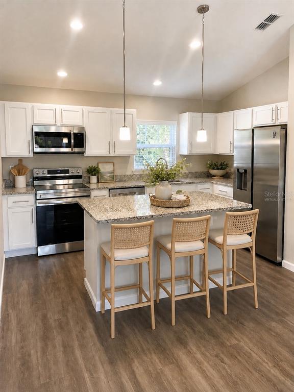 A kitchen features white cabinets, granite countertops, stainless steel appliances, and a central island — 4 LEMA PLACE, PALM COAST, FL