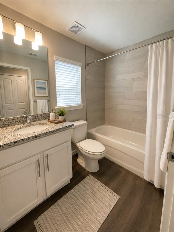 A bathroom features a white vanity with a granite countertop, a toilet, and a tiled tub — 4 LEMA PLACE, PALM COAST, FL