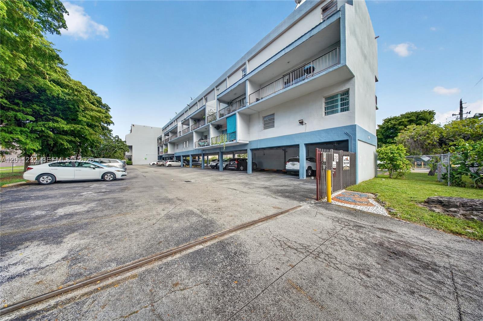 A multi-story apartment building features covered ground-level parking and an adjacent asphalt lot — 399 NW 72nd Ave # 209, Miami FL 33126, MIAMI, FL
