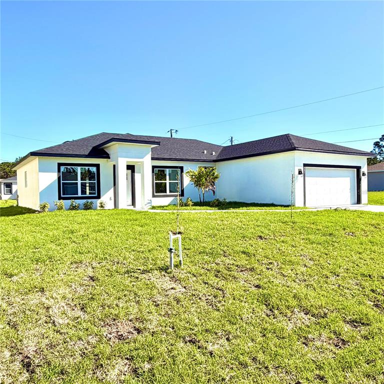 A single-story white house with a dark roof and a two-car garage sits on grass — 487 ALAMO STREET SE, PALM BAY, FL