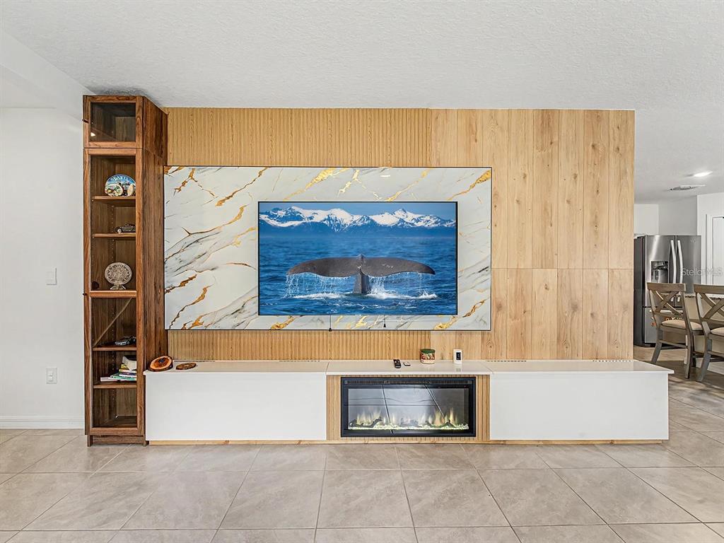 A living room features a wood-paneled accent wall with a marble-framed television and fireplace console — 13484 MYLION WAY, SPRING HILL, FL