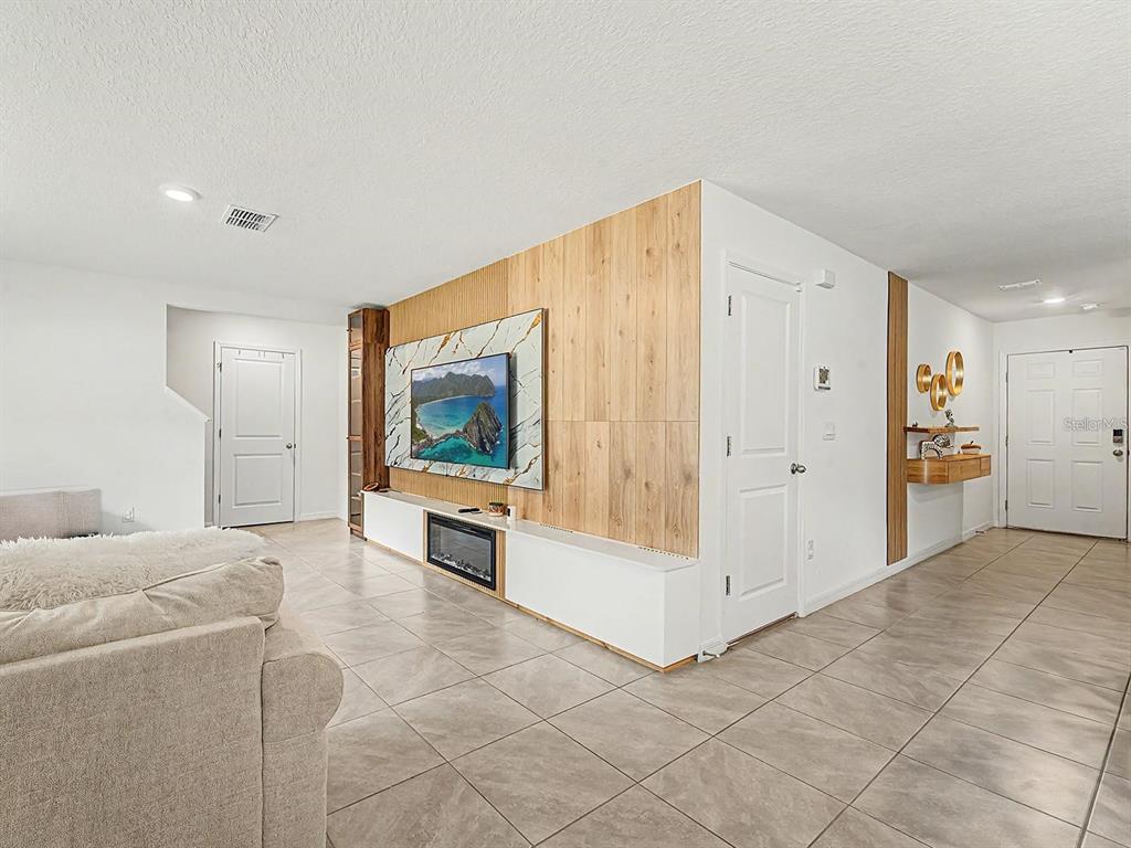 A living room features a wood-paneled accent wall with a mounted television and fireplace console — 13484 MYLION WAY, SPRING HILL, FL