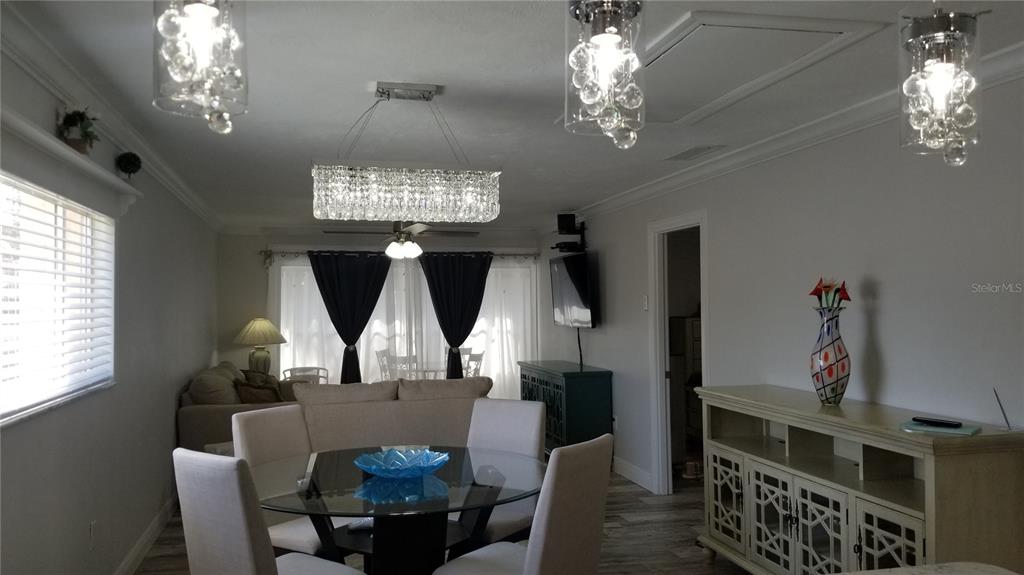 A dining area features a glass-topped table, upholstered chairs, and crystal light fixtures — 2772 WOODGATE LANE UNIT 28, SARASOTA, FL