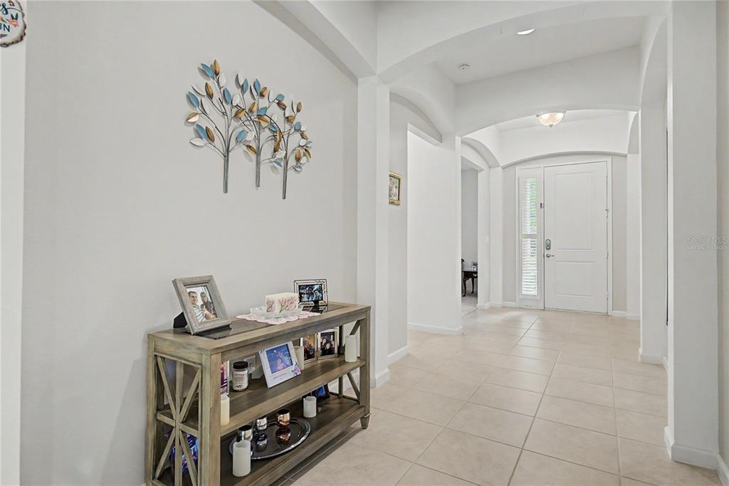 A foyer features a wooden console table, wall art, and tile flooring leading to a door — 3820 BOWFIN TRAIL, KISSIMMEE, FL