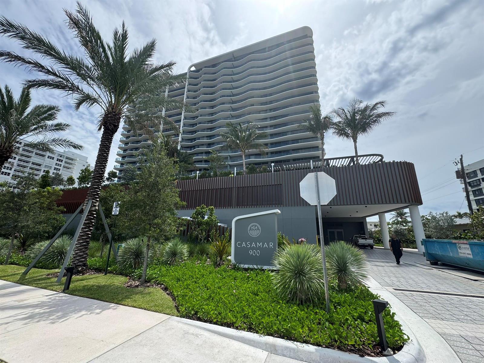 A modern high-rise building with wavy balconies stands behind a landscaped entrance sign — 900 N Ocean Boulevard, Pompano Beach FL 33062, POMPANO BEACH, FL