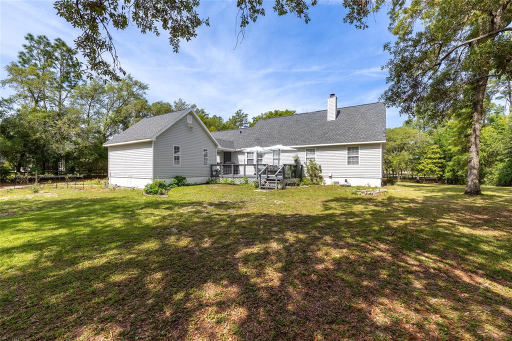 A light gray house with a deck and a large, grassy backyard surrounded by trees — 5801 SW 140TH AVENUE, OCALA, FL