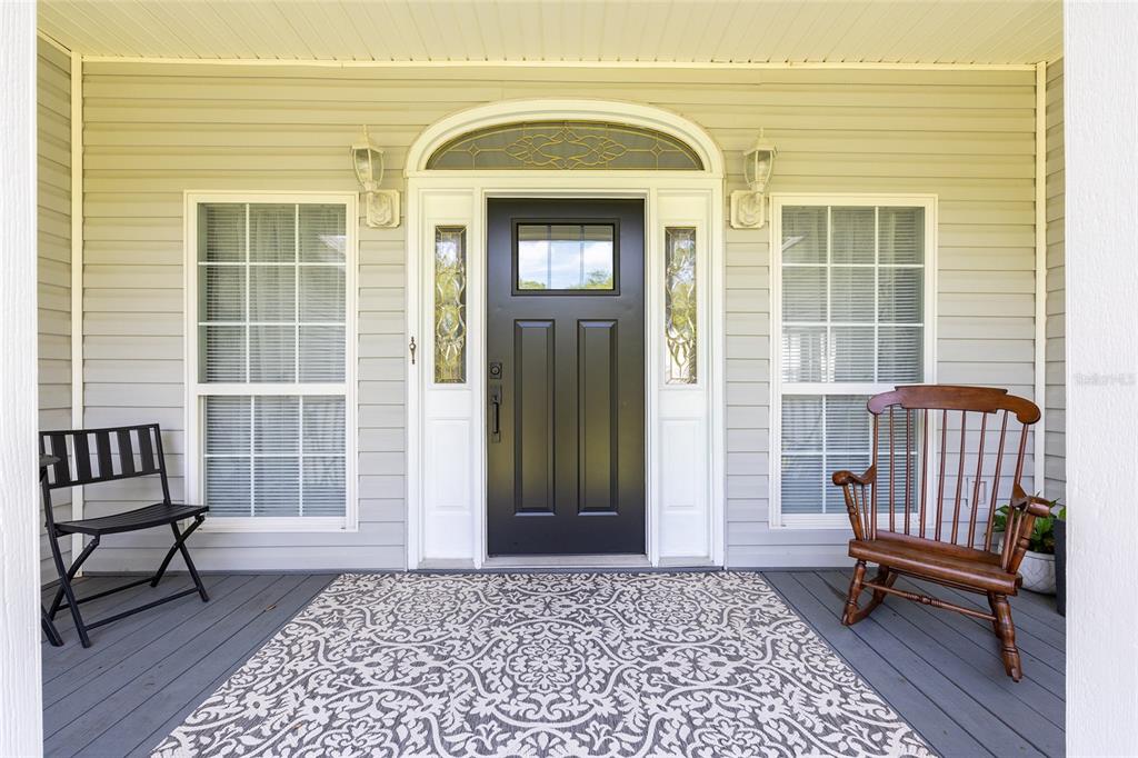 A front porch features a black door, two windows, a patterned rug, and two chairs — 5801 SW 140TH AVENUE, OCALA, FL