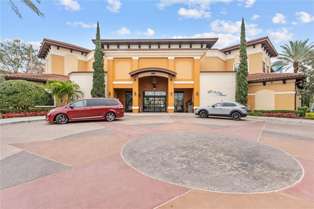 A two-story building with a circular driveway, two parked cars, and tall cypress trees — 12544 FLORIDAYS RESORT DRIVE, ORLANDO, FL