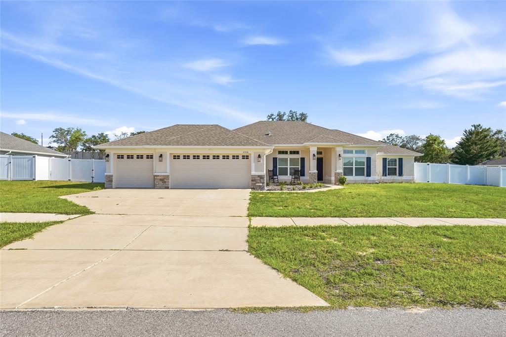 A single-story house with a three-car garage, light-colored siding, and a large front lawn — 12536 SUNSET WOODS DRIVE, SPRING HILL, FL
