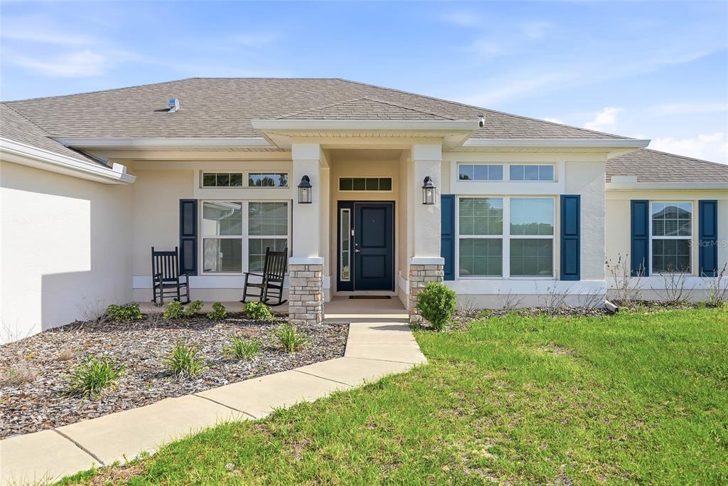 The exterior of a single-story house features a covered entryway, blue shutters, and a walkway — 12536 SUNSET WOODS DRIVE, SPRING HILL, FL