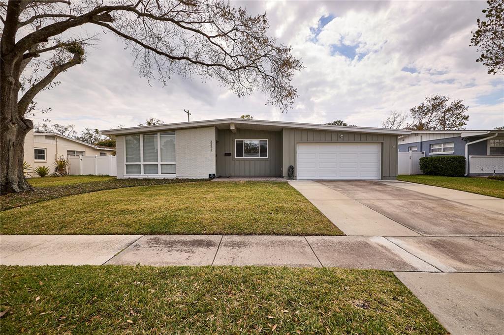 A single-story house with a white brick facade, a two-car garage, and a large tree — 3312 NAKORA DRIVE, TAMPA, FL