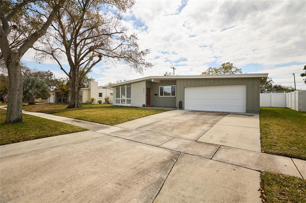 A single-story house with a white brick facade, green siding, and a two-car garage — 3312 NAKORA DRIVE, TAMPA, FL