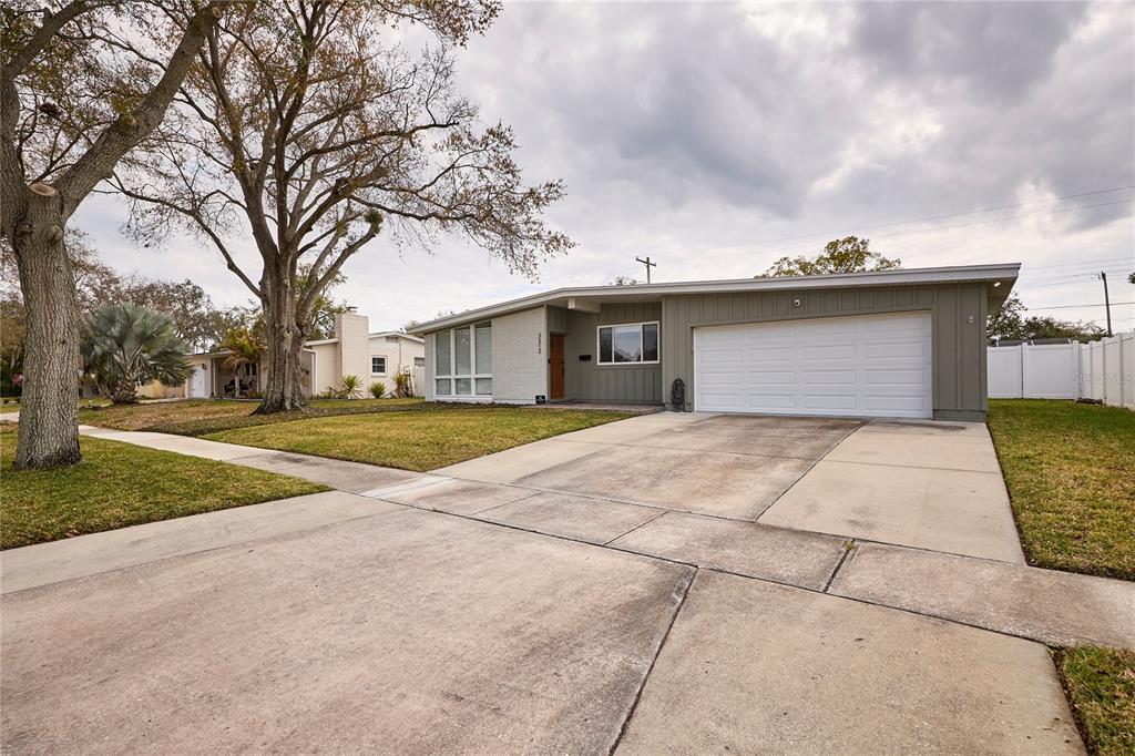 A single-story house with a white garage door, gray siding, and a concrete driveway — 3312 NAKORA DRIVE, TAMPA, FL