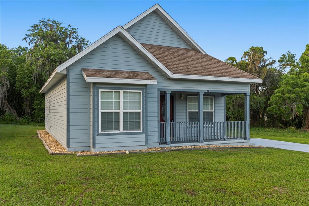 A light blue, single-story house with a covered front porch and a brown shingled roof — 535 W SILVER SPRINGS PLACE, OCALA, FL