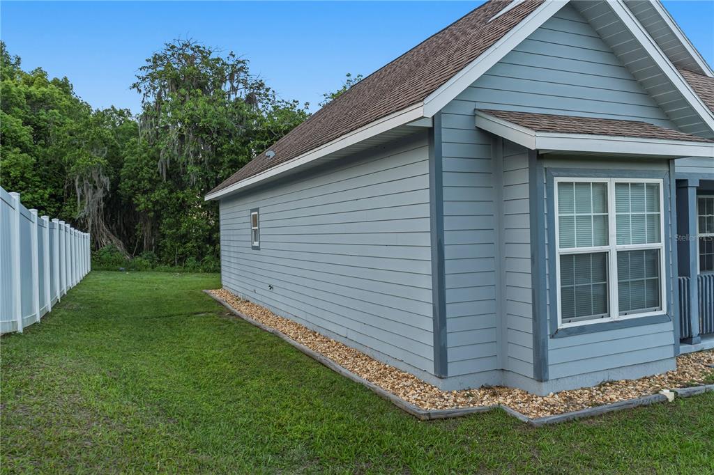 The exterior side view of a blue house features horizontal siding, a small window, and gravel — 535 W SILVER SPRINGS PLACE, OCALA, FL