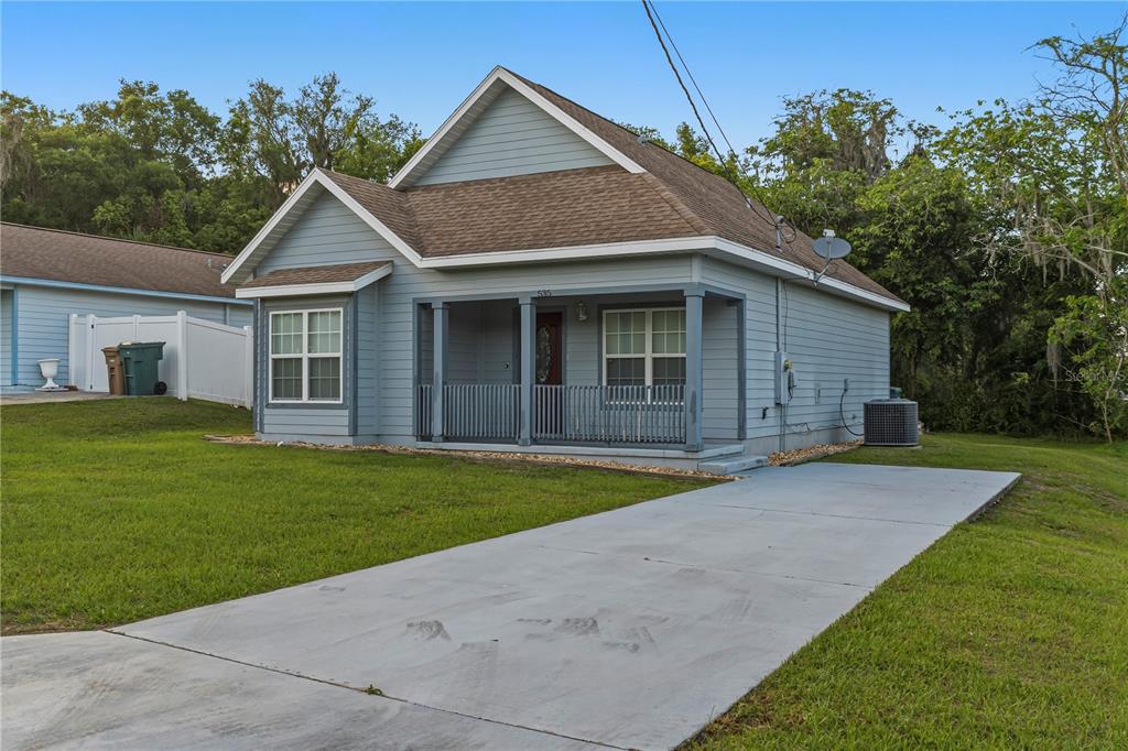 A blue, single-story house with a front porch, brown shingled roof, and concrete driveway — 535 W SILVER SPRINGS PLACE, OCALA, FL