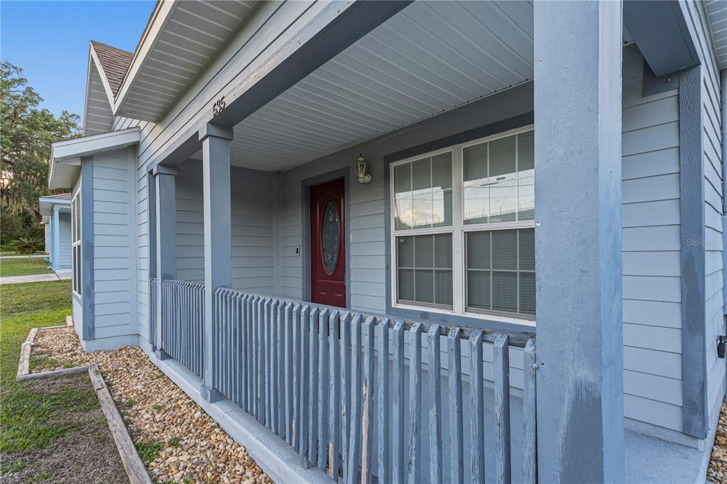 A blue house features a covered front porch with a wooden railing and red door — 535 W SILVER SPRINGS PLACE, OCALA, FL