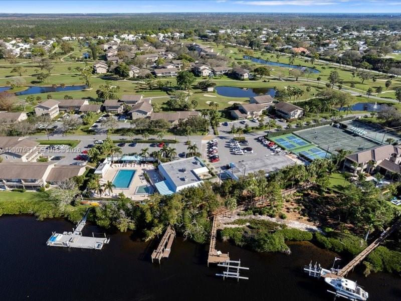 An aerial view shows a residential complex with a pool, tennis courts, and boat docks — 9169 SE Riverfront Ter # M, Jupiter FL 33469, JUPITER, FL