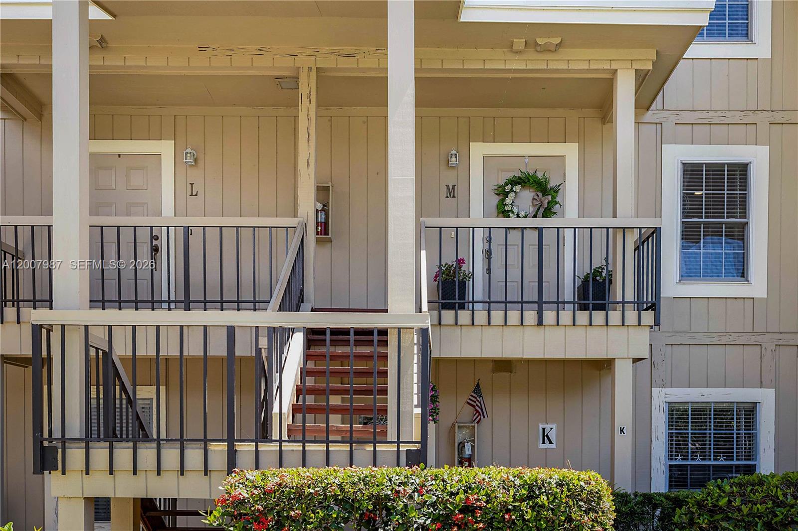 The exterior of a multi-story apartment building features staircases, balconies, and labeled unit doors — 9169 SE Riverfront Ter # M, Jupiter FL 33469, JUPITER, FL