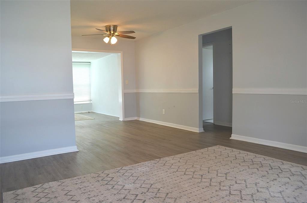 An interior view shows a living area with light gray walls, white wainscoting, and wood-look flooring — 9632 42ND STREET N, PINELLAS PARK, FL