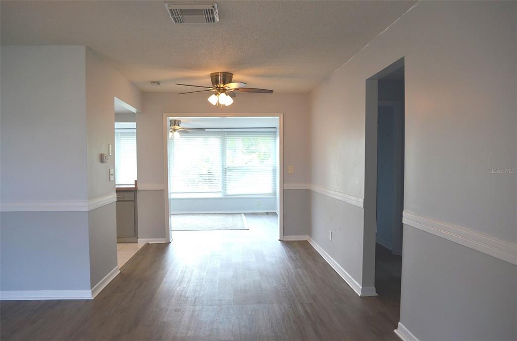 A dining area with light gray walls, white chair rail molding, and wood-look flooring — 9632 42ND STREET N, PINELLAS PARK, FL